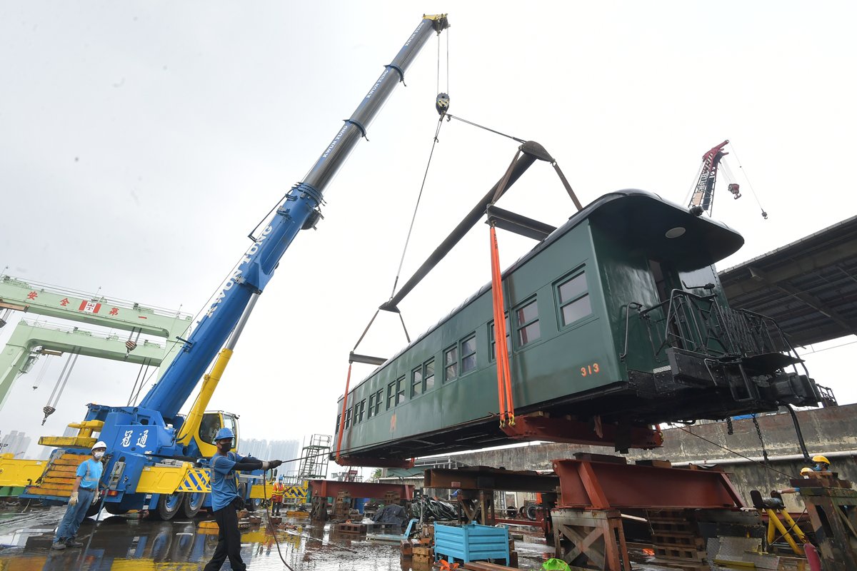小心翼翼:  工人以吊臂將313號火車卡吊上拖架，準備運送。