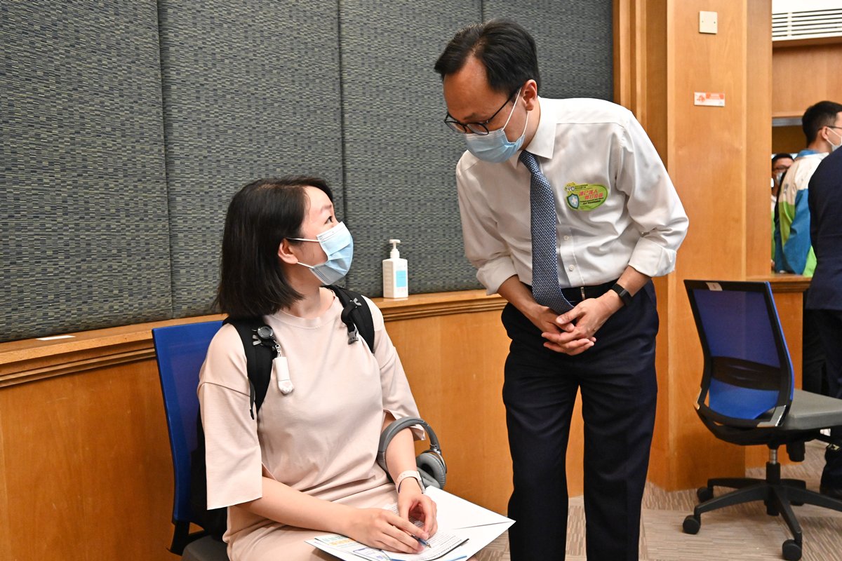 響應:  聶德權（右）到訪浸會大學，視察該校學生和教職員接種2019冠狀病毒病疫苗的情況，並與準備接種的大學職員交談。