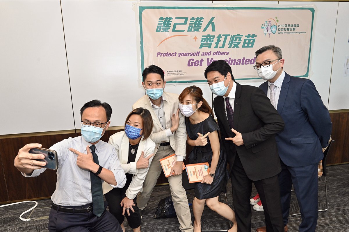 同心同德:  聶德權（左一）視察政府外展接種服務隊到AXA安盛為員工和代理人接種疫苗的情況。