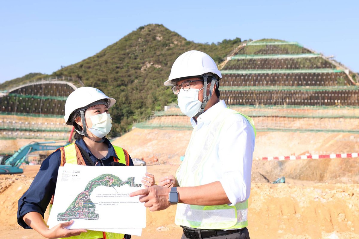 基建惠民:  黃偉綸（右）聽取土拓署北拓展處工程師陳曉彤簡介署方如何在大石磨山透過清理和平整土地，為古洞北新發展區建造食水和沖廁水配水庫。