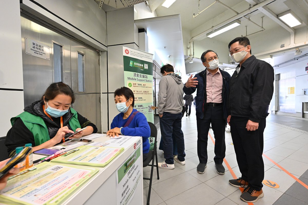 便利申請:  薛永恒（右）視察設於港鐵大埔墟站的流動支援站，聽取資科辦人員講解外展隊如何協助市民申請港康碼。