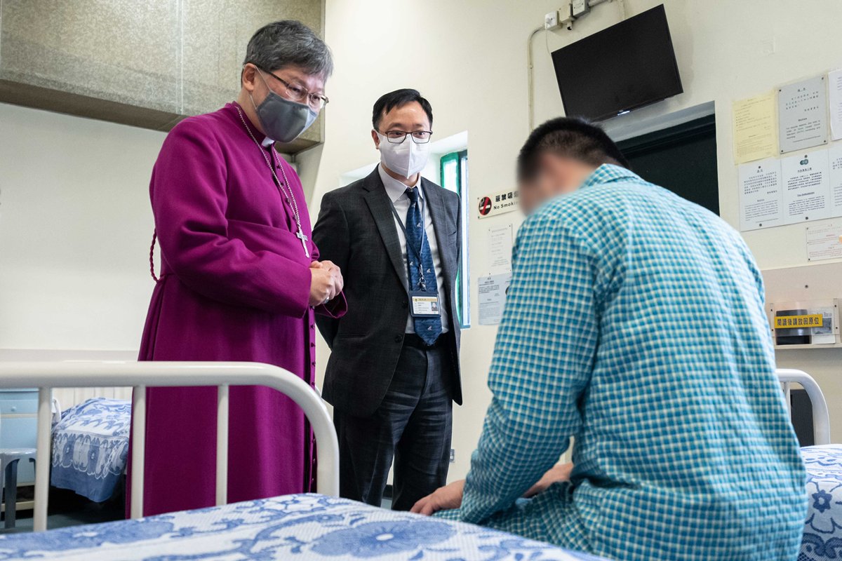 乃役於人:  陳謳明（左）12月23日到白沙灣懲教所醫院探望患病在囚人士。旁為懲教署副署長黃國興（中）。