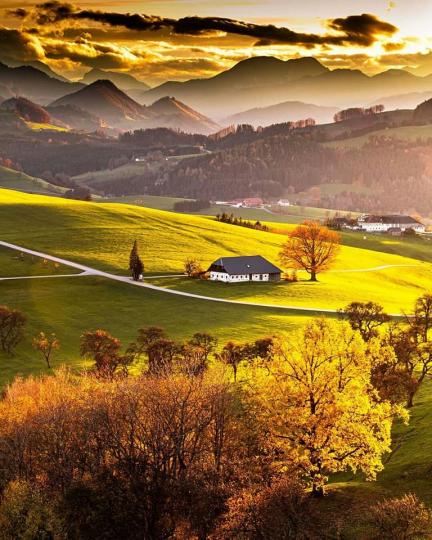 美如油畫的秋季奧地利，層層疊疊的山峰被夕陽壟罩，朦朧光線超夢幻...