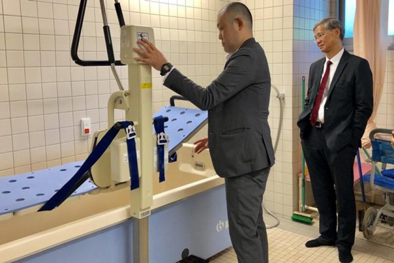 護理示範: 羅致光(右)在東京參觀一間安老院,觀看職員示範輔助設施,協助長期臥床或行動不便的長者沐浴。 護理示範: 羅致光(右)在東京參觀一間安老院,觀看職員示範輔助設施,協助長期臥床或行動不便的長者沐浴。
