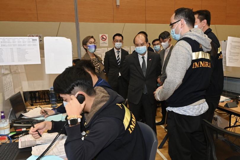 不辭勞苦:  張建宗（中）與辦公室的入境事務處人員交談，肯定他們的努力。