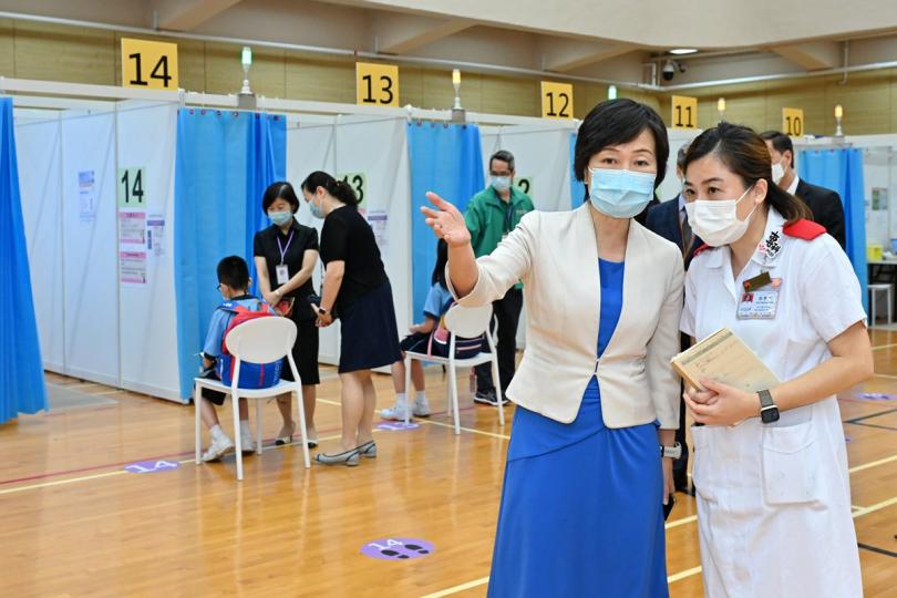 了解流程:  粉嶺官立小學學生到龍琛路體育館社區疫苗接種中心接種2019冠狀病毒病疫苗，蔡若蓮（前排左）到場視察，了解疫苗接種流程。