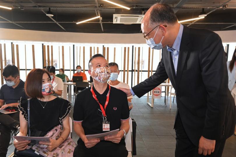 顧己及人:  陳帆（右）與準備接種新冠疫苗的九巴員工和家屬交談。