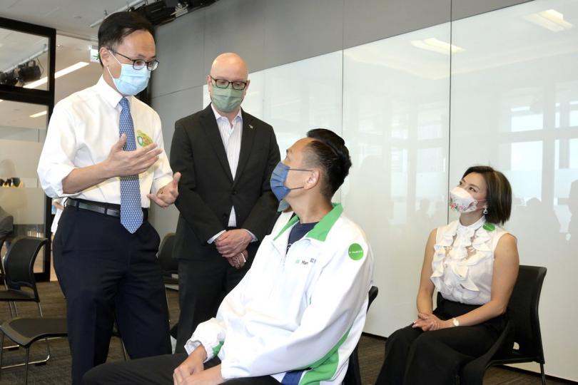 保障健康: 聶德權(左一)視察政府外展接種服務隊於宏利香港提供疫苗接種的情況,並與準備接種疫苗的人士交談。 保障健康: 聶德權(左一)視察政府外展接種服務隊於宏利香港提供疫苗接種的情況,並與準備接種疫苗的人士交談。
