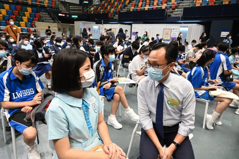 團體預約:  聶德權（前排右）在伊利沙伯體育館社區疫苗接種中心與完成接種疫苗的中學生交談。