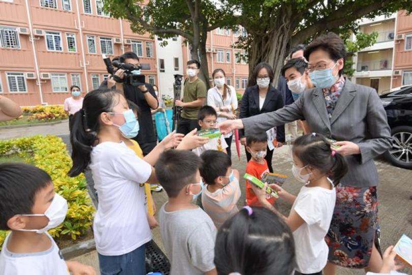 與民同樂:  林鄭月娥（右一）到訪過渡性房屋項目期間，向小朋友派發糖果。