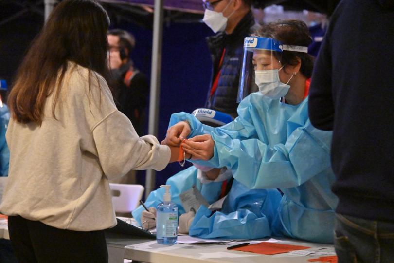 易於識別:  工作人員在東涌受限區域為受檢人士戴上手環，證明已接受檢測。