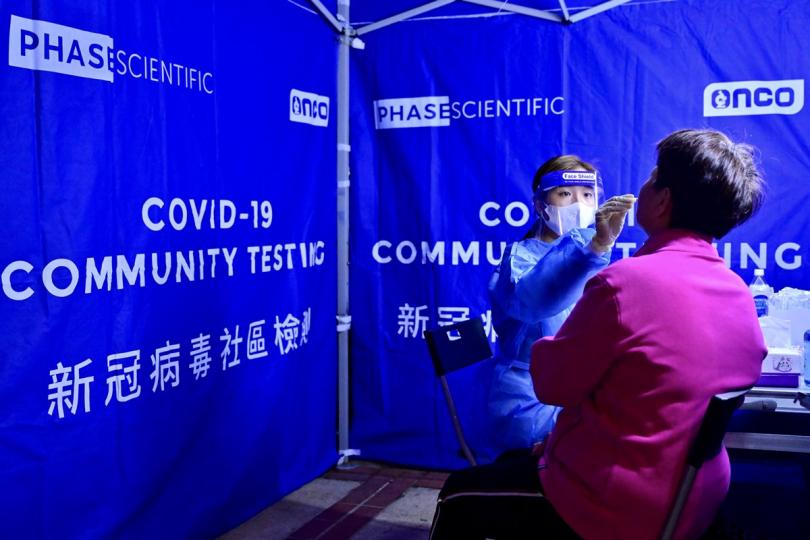 收集樣本:  工作人員在屯門受限區域為受檢人士以咽喉和鼻腔合併拭子採樣。