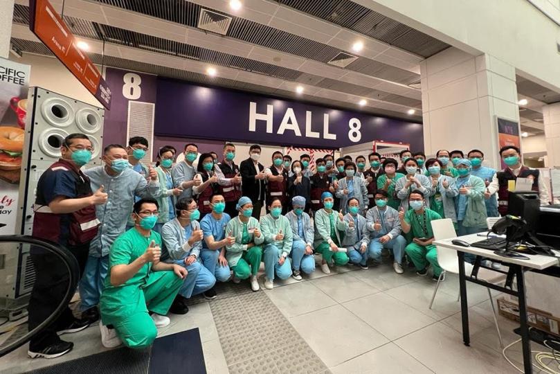 適切治療:  陳肇始（第二排右八）了解亞博館新冠治療中心醫護人員治療護理新冠肺炎病人的工作，並與內地援港醫療隊交流。