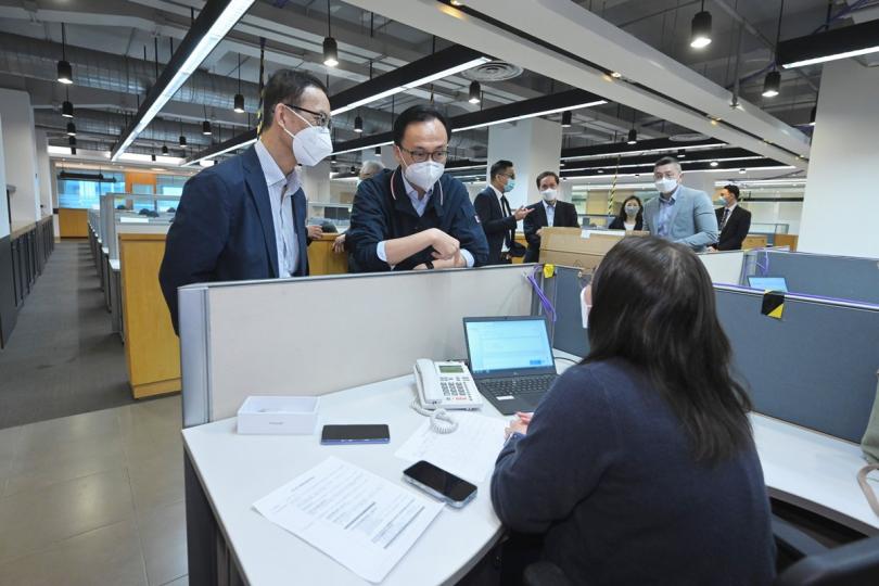 眾志成城:  聶德權（左二）與在電話熱線中心協助市民登記疫苗到戶接種服務的明愛專上學院學生交談。