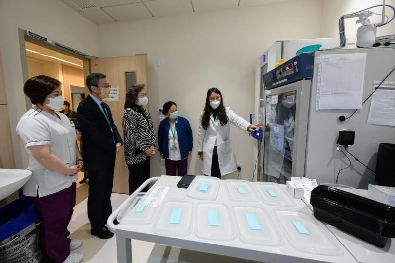 嚴格標準:  楊何蓓茵（中）到訪中文大學醫院社區疫苗接種中心，其間聽取醫護人員介紹復必泰二價疫苗的儲存情況。   