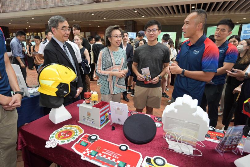 服務市民:  楊何蓓茵（左二）在香港大學舉‍行的政府職位招聘展覽，聽取消防處職員介紹部門職系資訊。