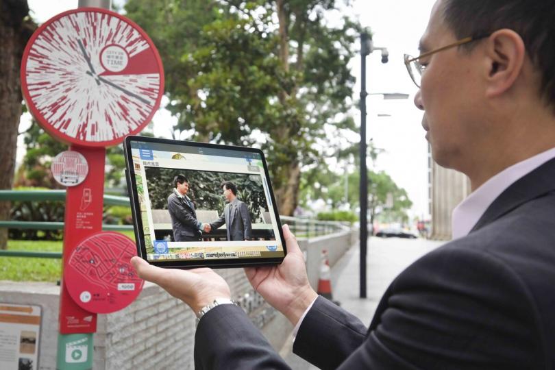 回顧經典:  楊潤雄使用「城市景昔」手機應用程式新設功能，現場重溫經典香港電影片段。