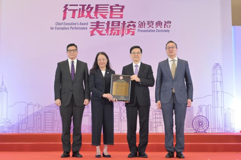 典範: 李家超(右二)向廖李可期(左二)頒授獎狀。旁為律政司司長林定國(右一)和保安局局長鄧炳強。 典範: 李家超(右二)向廖李可期(左二)頒授獎狀。旁為律政司司長林定國(右一)和保安局局長鄧炳強。