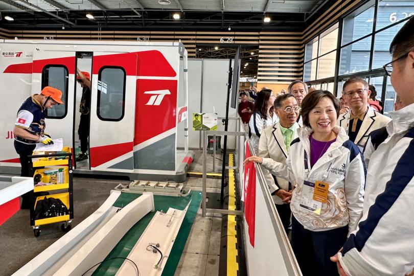 初登賽場:  蔡若蓮（前排右二）參觀大賽的軌道車輛技術比賽場地。中國香港代表團首次派出代表參與此項目。