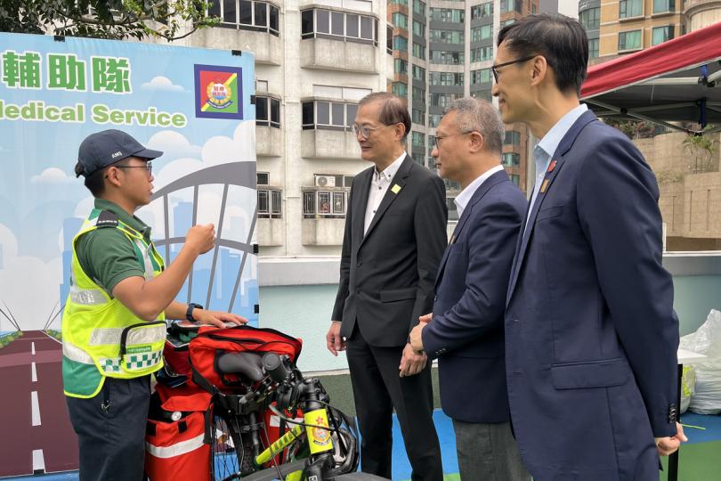 深入了解:  盧寵茂（左二）出席開放日，聽取醫療輔助隊人員介紹急救單車服務。
