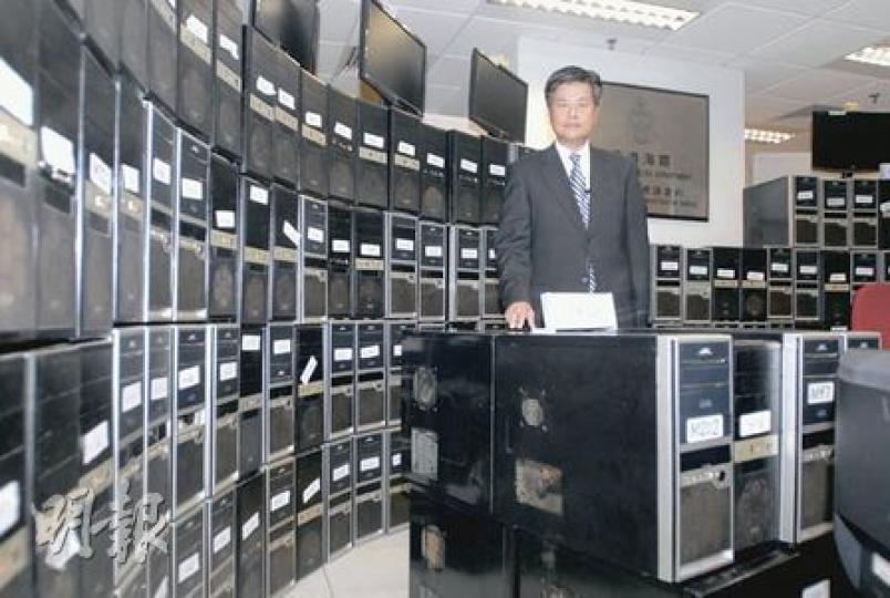 海關版權及商標調查科署理高級督察連順賢展示在荃灣一間網吧內檢獲的258部電腦，全部均載有「老翻」軟件。（劉友光攝）