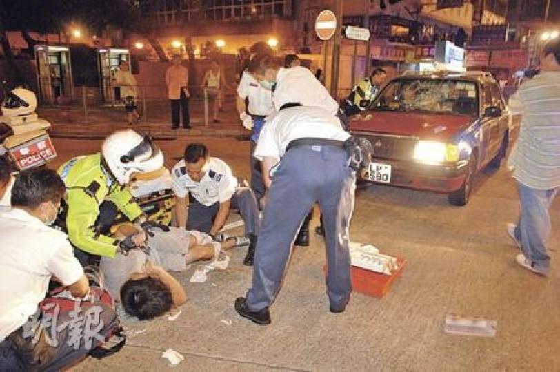 踏單車被的士撞倒的少年，被拋上的士車頭後撼裂擋風玻璃再拋飛約4米外，左腿骨折倒地，救護員事後在場急救。（胡永輝攝）