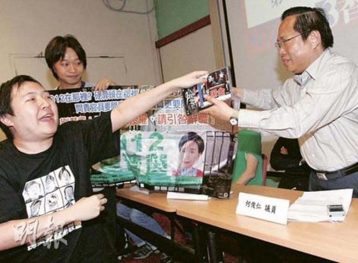 民主黨主席何俊仁（右）昨在論壇上受盡批評，「豬面男」更向何俊仁送上《黑金》、《Laughing Gor之变節》的電影光碟，以及一塊要求劉慧卿就違反「爭取2012雙普選」承諾而引咎辭職的橫額，諷刺該黨在政改中妥協。（李紹昌攝）
