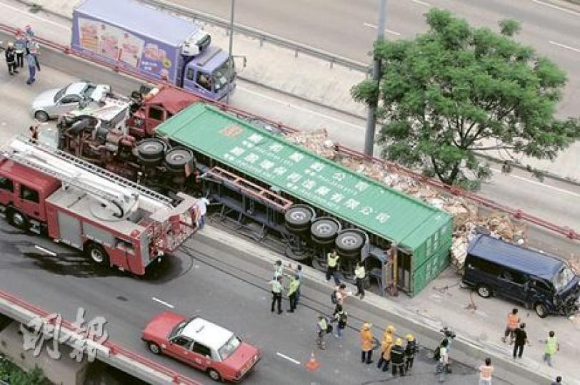 滿載回收廢紙的貨櫃車失控撞壆後，跨過路中石壆在對行線翻側，連撞5車，釀成11人受傷。（衛永康攝）貨櫃車翻過對行線後與5車連環相撞，6車亂作一團。（衛永康攝）最先與翻側貨櫃車相撞的客貨車，被廢紙磚剷起傾側推向橋邊鐵欄，險跌落30呎橋底，消防用繩將車身拉住。（衛永康攝）拖車司機重傷被困車廂，消防員花近45分鐘將他救出，送院搶救後命危。（衛永康攝）