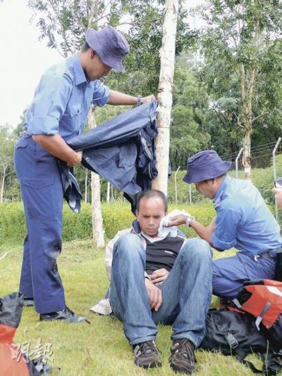 炎夏之時常有行山者受傷或中暑，圖中民安隊員示範如何為中暑者急救，重點是同行者應為患者遮擋陽光，並以濕衣物或毛巾抹中暑者腋下以助散熱。（馮樂琳攝）