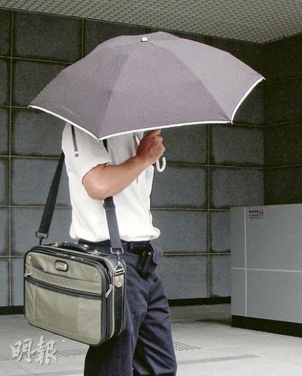 被告何廣明獲准保釋候審,離開法庭前嘗試擺脫記者,以雨傘掩面離開。(梁珮珊攝) 被告何廣明獲准保釋候審,離開法庭前嘗試擺脫記者,以雨傘掩面離開。(梁珮珊攝)