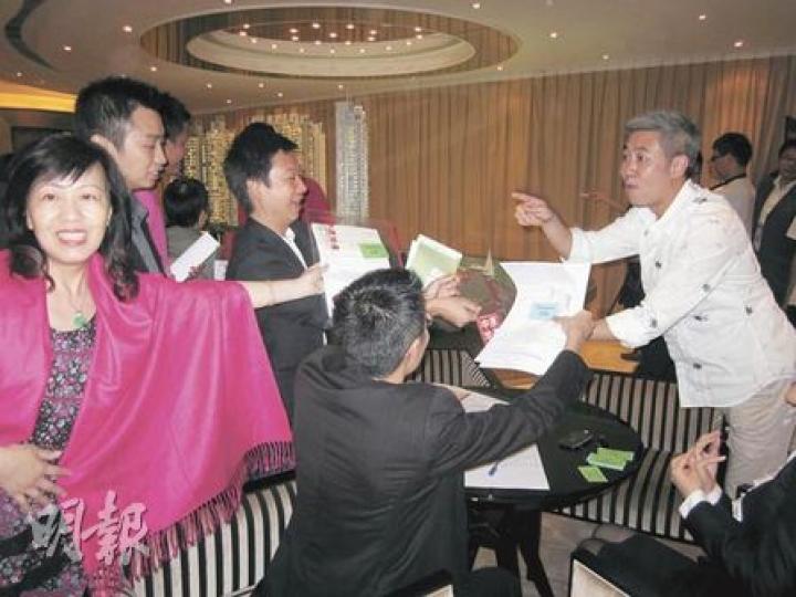 「南灣」昨日主力售賣1、2房單位，推出的66伙中，截至晚上8時已售出九成，亦即接近沽清。圖為售樓處內，地產代理爭相向主管遞交客人資料的情况。（林可為攝）