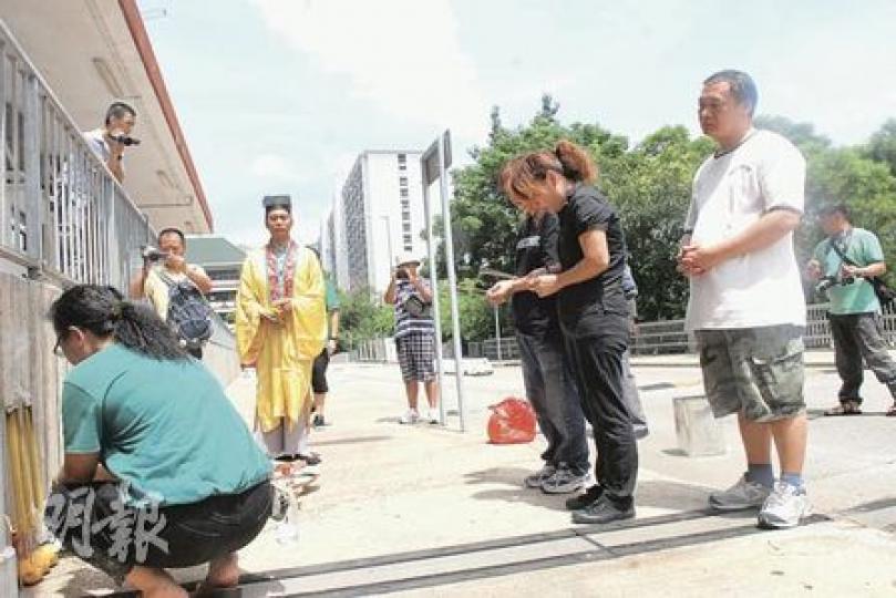 竹園南邨倫常慘案中身亡母女的多名家屬，昨午在慘劇現場路祭，女死者陳秀麗的姊姊（黑衣）情緒激動，契媽蕭艷玲（綠衣）則協助打點儀式。（林鍚禮攝）