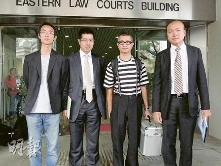 街頭藝人蘇春就（右二）在公民黨九龍東支部主席余冠威（左一）陪同下，拿着「法寶箱」出庭，但未有在庭外露一手。他由李柱銘之子、大律師李祖詒（左二）代為辯護。（何偉畧攝）