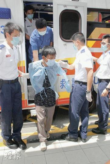 兩名越南籍非法入境者被捕後報稱患有傳染病，被安排送院檢驗，兩人要穿防護衣，救護員亦戴上口罩戒備。（屈俊樂攝）