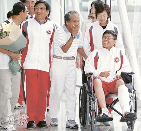 中流彈受傷的港隊女棒球員卓莞爾（前右），昨早與隊友返抵香港，她仍要坐輪椅，與旁人有說有笑。（李紹昌攝）