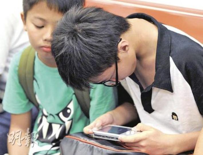 鐵路車廂內不難發現很多小朋友埋首打機,專家警告,這是導致近視加深的元兇之一,無論是看書或打機,護眼距離應保持在30厘米,即約一張A4紙打直的長度。(何家達攝) 鐵路車廂內不難發現很多小朋友埋首打機,專家警告,這是導致近視加深的元兇之一,無論是看書或打機,護眼距離應保持在30厘米,即約一張A4紙打直的長度。(何家達攝)
