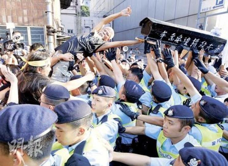 四五行動成員古思堯抬起一副4呎半長的黑色棺材,但警方以大型物件影響公眾安全為由,拒絕示威者抬棺材到中聯辦門前,雙方爆發衝突。(李紹昌攝)警方使用胡椒噴霧驅趕示威者,社民連「長毛」梁國雄也「中招」,雙眼不能睜開,其他人即時不斷向他的眼睛灌水,冲走噴霧。(李紹昌攝) 四五行動成員古思堯抬起一副4呎半長的黑色棺材,但警方以大型物件影響公眾安全為由,拒絕示威者抬棺材到中聯辦門前,雙方爆發衝突。(李紹昌攝)警方使用胡椒噴霧驅趕示威者,社民連「長毛」梁國雄也「中招」,雙眼不能睜開,其他人即時不斷向他的眼睛灌水,冲走噴霧。(李紹昌攝)