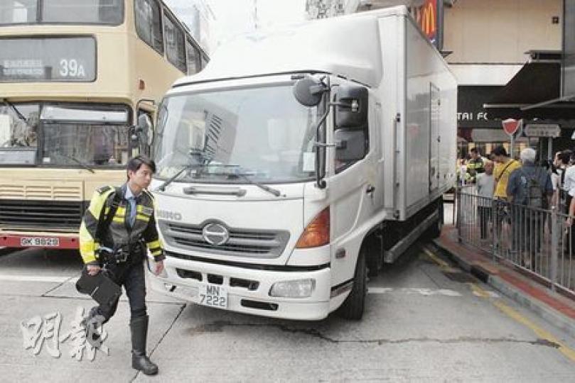 密斗貨車轉入沙嘴道時,左尾轆貼近行人路石壆,把一名站於鐵欄外等候過路的婦人夾困在車身與鐵欄之間。(蘇偉明攝) 密斗貨車轉入沙嘴道時,左尾轆貼近行人路石壆,把一名站於鐵欄外等候過路的婦人夾困在車身與鐵欄之間。(蘇偉明攝)