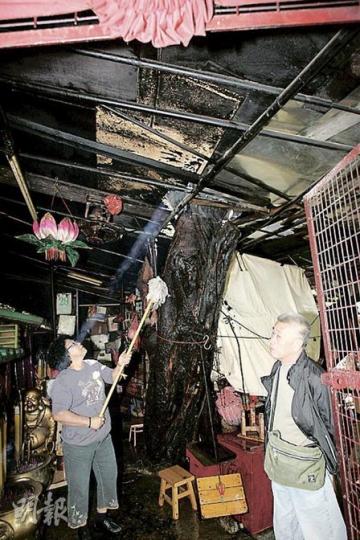 「五華師母」廟內有一棵細葉榕貫穿屋頂,平日不少善信前來上香,火警被救熄後,余太(左)趕緊清理燒焦的屋頂和樹幹被熏黑部分。(黃雄攝) 「五華師母」廟內有一棵細葉榕貫穿屋頂,平日不少善信前來上香,火警被救熄後,余太(左)趕緊清理燒焦的屋頂和樹幹被熏黑部分。(黃雄攝)