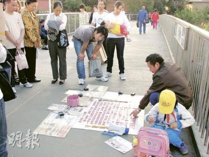 在無工打時，覃父就上街乞討，曉艷在一旁做功課，吸引不少路人關注的目光。（明報記者攝）每當假期，曉艷就到工廠剪線頭。（明報記者攝）