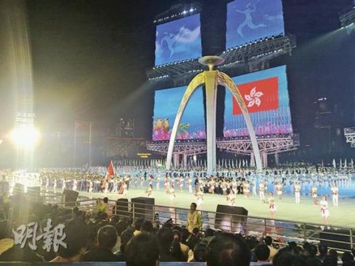 由學生扮演的「香港隊」入場。後為火炬台。（明報記者攝）