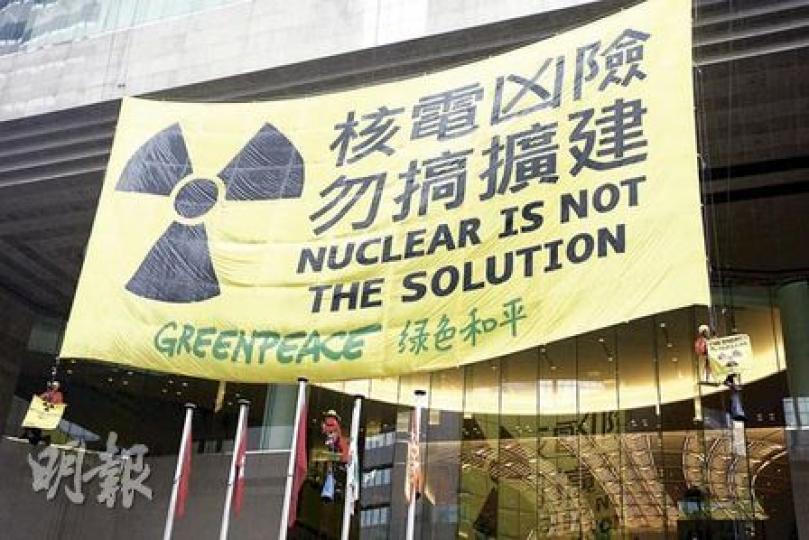 綠色和平3名成員在舉行C40論壇的會展舊翼外牆游繩而下，掛起「核電凶險 勿搞擴建」巨型橫額，要求港府立即擱置增加核電的計劃。（李紹昌攝）環境局長邱騰華（中）昨出席國際氣候會議C40論壇記者會時，指全球專家普遍認為核電是可大規模應用的「零排放」發電方式之一，綠色和平即批評他錯誤引述權威言論。（李紹昌攝）