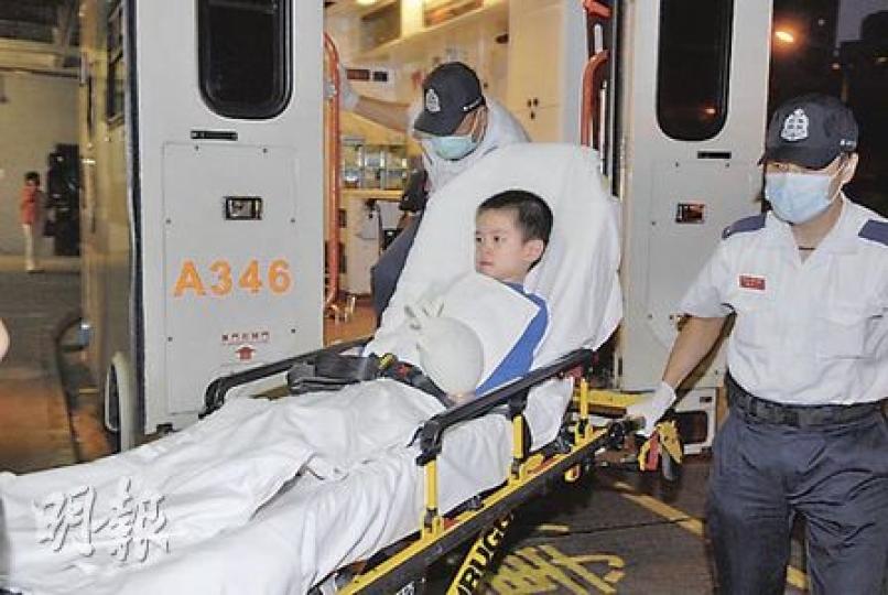 穿涼鞋捲入扶手電梯致左腳腳趾受傷的男童，送院時手持救護員送贈的哈哈笑手套。（曾立本攝）