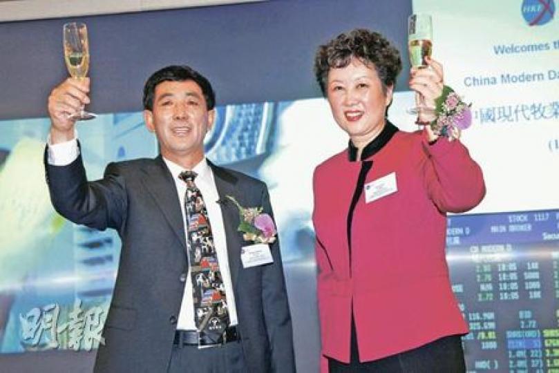 現代牧業在港首日上市,董事長鄧九強(左)和總裁高麗娜(右)舉杯慶祝之時,其身後的熒幕顯示屏,一開市便顯示其股票跌穿招股價。(陳智良攝) 現代牧業在港首日上市,董事長鄧九強(左)和總裁高麗娜(右)舉杯慶祝之時,其身後的熒幕顯示屏,一開市便顯示其股票跌穿招股價。(陳智良攝)