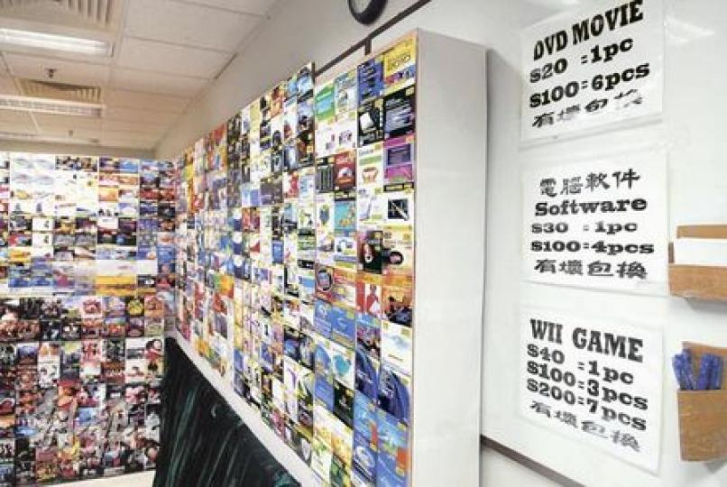 翻版光碟販子以減價吸引顧客，電影DVD每隻賣20元，買6隻收100元，有壞包換，客人隨時可用紙筆（圖右）落單購買。（何朝財攝）
