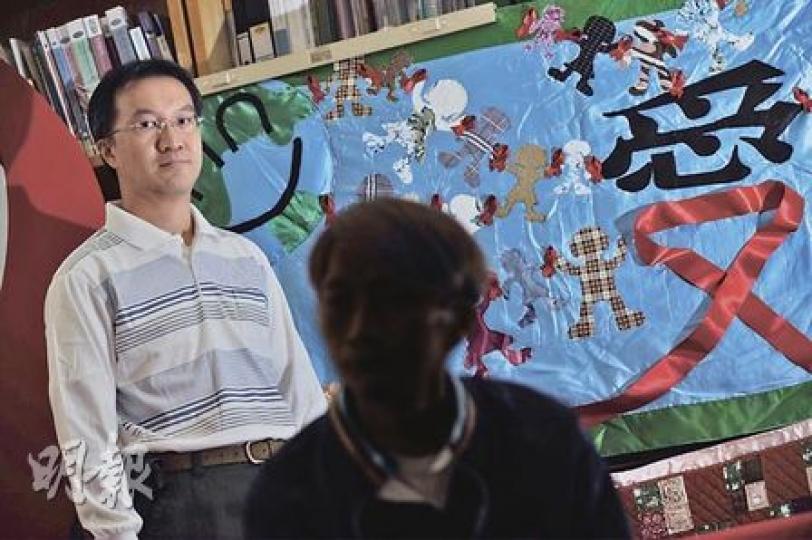 義工Tim（左）及愛滋病人Eddie（右）一同製作的掛被，以藍色為主調，縫上手牽手的不同膚色人形布偶，比喻愛與關懷能掃除隔膜。（何家達攝）
