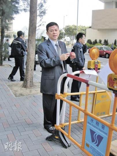 百營環球資源主席施展望步出法院數分鐘後在法院正門對開被人淋潑紅色顏料，額頭、西裝正面及後頸等位置都有顏料，案發後他站在一旁清理，其後不滿被記者拍照。（梁珮珊攝）按現場環境，相信施展望是在登上七人車時被人淋漆，其代表律師莊智宇（右，灰色西裝）亦一樣遭殃。案發後司機（左）幫忙清理現場。（梁珮珊攝）