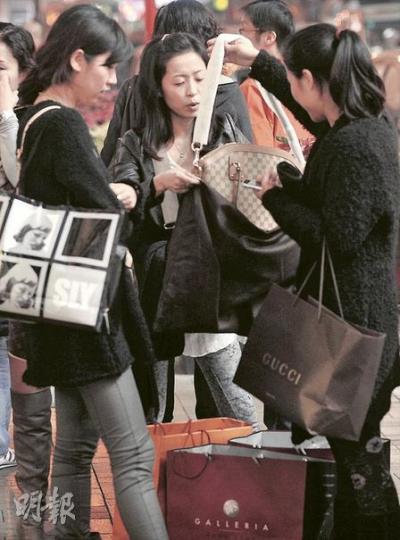 中國海關規定國民只能帶價值5000元以內的物品過境，否則就會被徵稅，內地遊客遂各出其謀避稅，有人買相機時先試拍幾張相片假扮自用，有人則索性即時打開名牌手袋，隨身攜帶，當作自用。（余俊亮攝）（明報製圖）