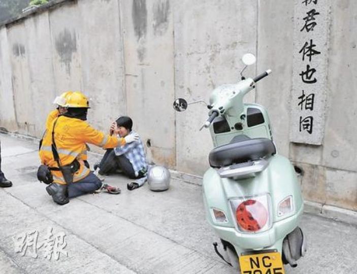 意外後，女鐵騎士坐在黄泥涌道的行人路等待救援，她右腳受輕傷，送院治理。（林錫禮攝）