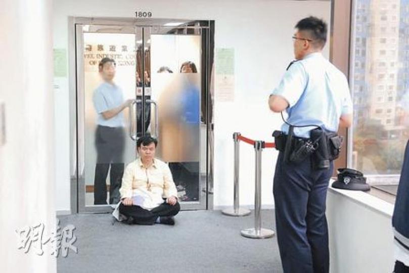導遊總工會會長黃嘉毅（黃衫者）昨日到旅遊業議會抗議下月推行「一團一導遊」措施，聲稱曾被保安員箍頸，報警後於議會門外靜坐抗議。（何朝財攝）